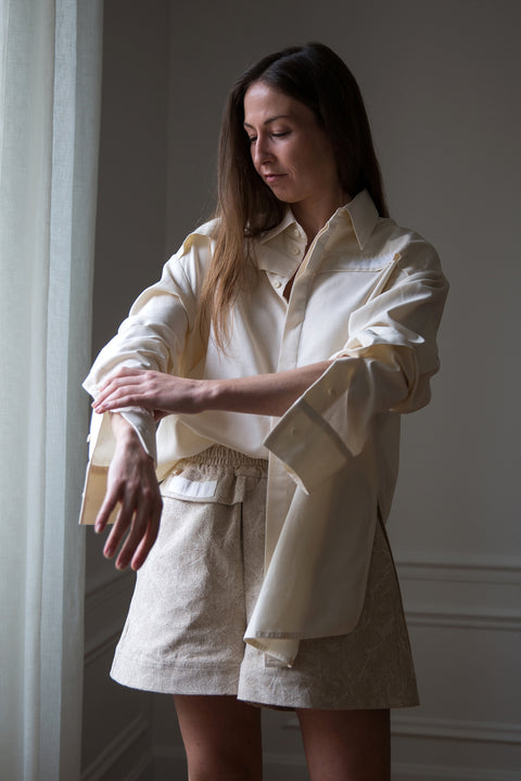 Lena is wearing White Canvas sustainable jacquard short shorts, size S. The jacquard short shorts have minimal modern aesthetics design allowing comfort and bringing self-confidence. This unique piece is made locally in Paris to reduce environmental impact and guarantee high quality and durability of the products.