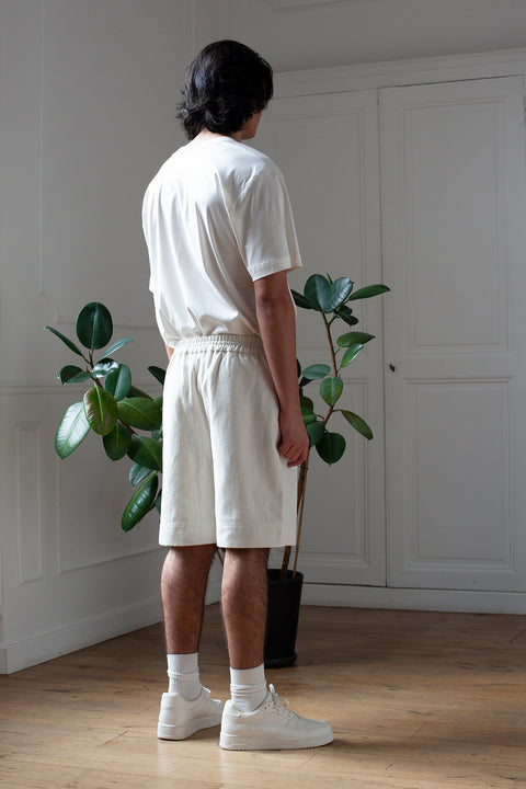 Medhi is wearing White Canvas sustainable denim genderless casual shorts, size M. The denim shorts have minimal modern aesthetics design allowing comfort and bringing self-confidence. This unique piece is made locally in Paris to reduce environmental impact and guarantee high quality and durability of the products.