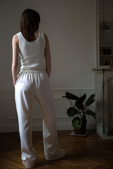 Dalva is wearing White Canvas sustainable light wool genderless, seasonless casual trousers, size S. The light wool trousers have minimal modern aesthetics design allowing comfort and bringing self-confidence. This unique piece is made locally in Paris to reduce environmental impact and guarantee high quality and durability of the products.
