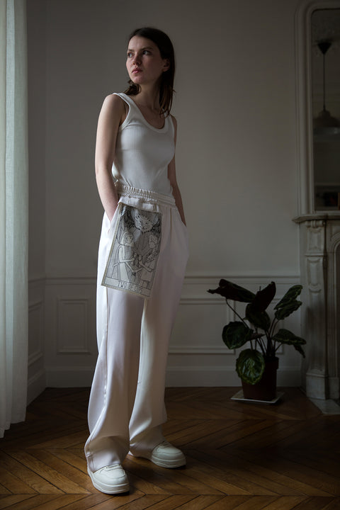 Dalva is wearing White Canvas sustainable light wool genderless, seasonless casual trousers, size S. The light wool trousers have minimal modern aesthetics design allowing comfort and bringing self-confidence. This unique piece is made locally in Paris to reduce environmental impact and guarantee high quality and durability of the products.