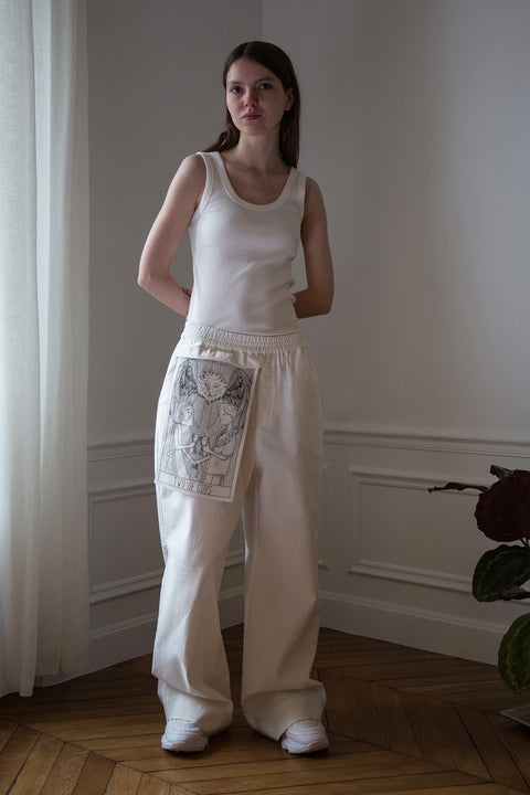 Dalva is wearing White Canvas sustainable cotton stripes genderless, seasonless casual checks trousers, size L. The white cotton stripes trousers have minimal modern aesthetics design allowing comfort and bringing self-confidence. This unique piece is made locally in Paris to reduce environmental impact and guarantee high quality and durability of the products.