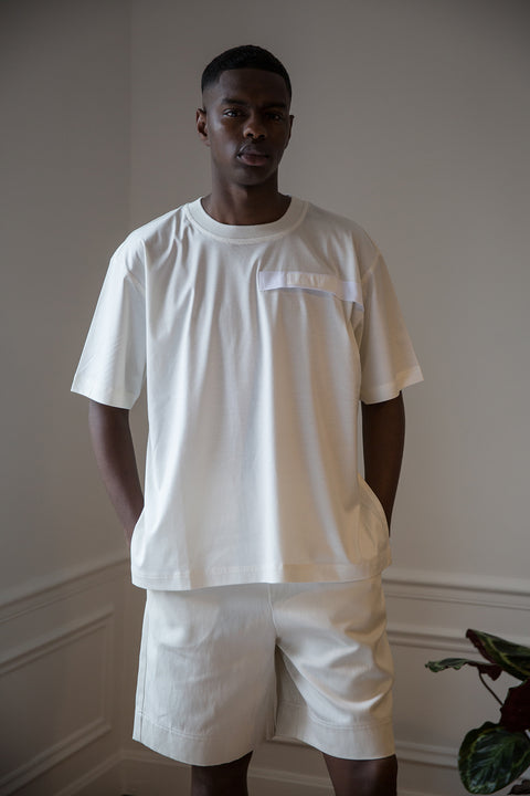 Thierno is wearing White Canvas sustainable off white cotton jersey oversized, genderless, seasonless t-shirt, one size. The off white cotton jersey t-shirt has minimal modern aesthetics design allowing comfort and bringing self-confidence. This unique piece is made locally in Paris to reduce environmental impact and guarantee high quality and durability of the products.