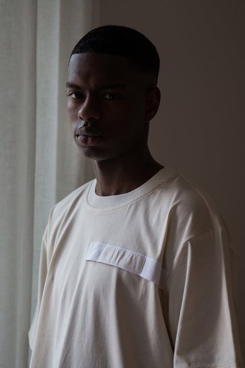 Thierno is wearing White Canvas sustainable natural cotton jersey oversized, genderless, seasonless t-shirt, one size. The natural cotton jersey t-shirt has minimal modern aesthetics design allowing comfort and bringing self-confidence. This unique piece is made locally in Paris to reduce environmental impact and guarantee high quality and durability of the products.