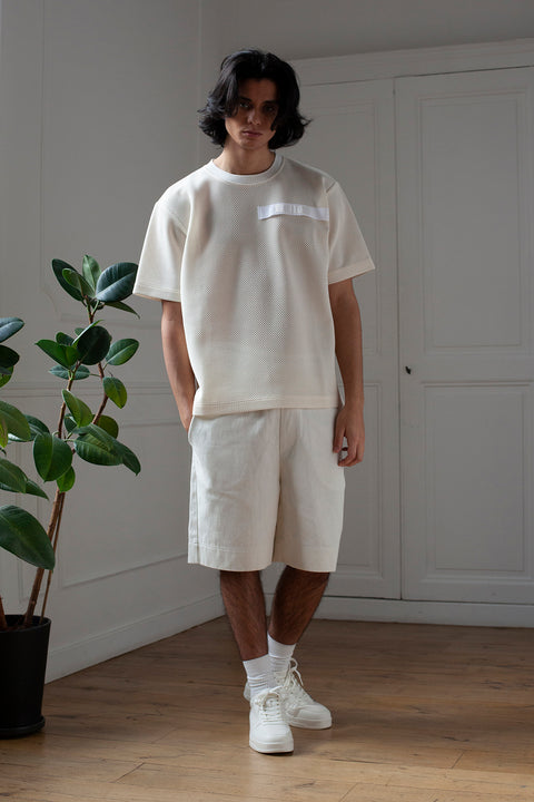 Medhi is wearing White Canvas sustainable mesh oversized, genderless, seasonless t-shirt, one size. The mesh t-shirt has minimal modern aesthetics design allowing comfort and bringing self-confidence. This unique piece is made locally in Paris to reduce environmental impact and guarantee high quality and durability of the products.