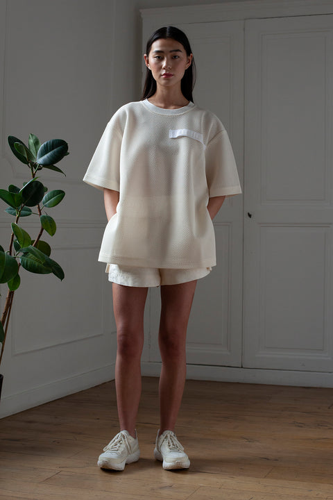 SiJia is wearing White Canvas sustainable mesh oversized, genderless, seasonless t-shirt, one size. The mesh t-shirt has minimal modern aesthetics design allowing comfort and bringing self-confidence. This unique piece is made locally in Paris to reduce environmental impact and guarantee high quality and durability of the products.