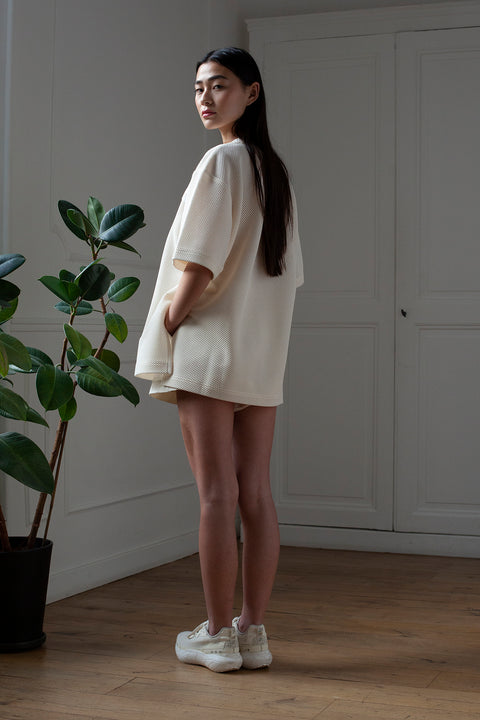 SiJia is wearing White Canvas sustainable mesh oversized, genderless, seasonless t-shirt, one size. The mesh t-shirt has minimal modern aesthetics design allowing comfort and bringing self-confidence. This unique piece is made locally in Paris to reduce environmental impact and guarantee high quality and durability of the products.
