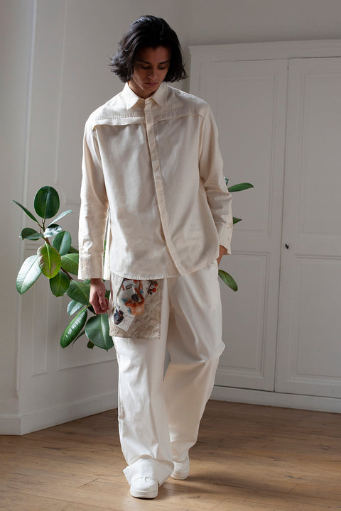 Medhi is wearing the White Canvas essential shirt styled with the Newspaper vertical panel made from deadstock cotton poplin. The panel has an exclusive print of a photo by the photographer Henrique Soares. Attach the panel to the essential pieces to personalize them and wear them your unique way. It is the perfect creative summer accessory.