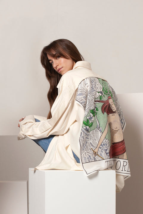 Léa is wearing the White Canvas ESSENTIAL SHIRT styled with THE WORLD foulard and square panel made from leftover deadstock silk fabric. The foulard has an exclusive design inspired by tarot cards drawn by the artist Maria Robla, printed with black artisanal eco-friendly ink locally in Paris and hand painted by the artist. Wear the foulard alone or attach it to the essential pieces to personalize them and wear them your unique way. Your perfect summer accessory. White Canvas x Maria Robla.
