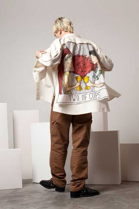 Clément is wearing the White Canvas ESSENTIAL SHIRT styled with THE TWO OF CUPS foulard and square panel made from leftover deadstock silk fabric. The foulard has an exclusive design inspired by tarot cards drawn by the artist Maria Robla, printed with black artisanal eco-friendly ink locally in Paris and hand painted by the artist. Wear the foulard alone or attach it to the essential pieces to personalize them and wear them your unique way. Your perfect summer accessory. White Canvas x Maria Robla.
