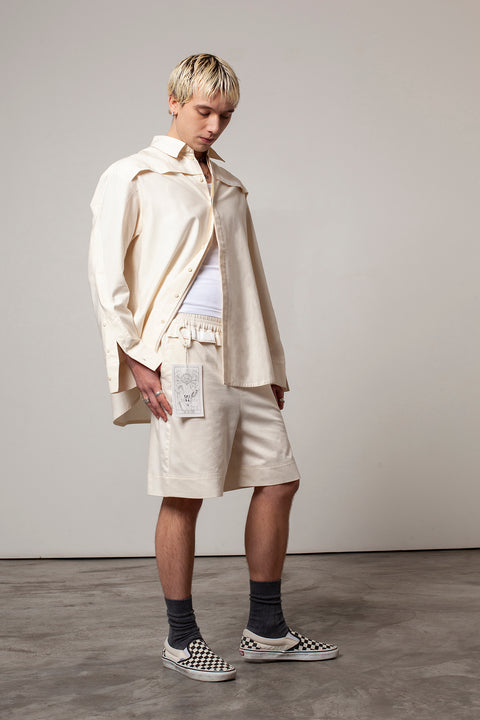 Clément is wearing the White Canvas ESSENTIAL SHORT styled with THE TWO OF CUPS tag made from leftover deadstock white cotton poplin. The black and white tag has an exclusive design inspired by tarot cards drawn by the artist Maria Robla and is printed in collaboration with RoStudio. Wear the tag alone or attach it to the essential pieces to personalize them. The tag is sold with key holder in recycled plastic made in collaboration with Samji Atelier. White Canvas x Maria Robla.