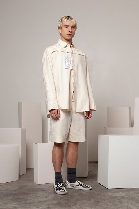 Clément is wearing the White Canvas ESSENTIAL SHRT styled with THE WORLD tag made from leftover deadstock white cotton poplin. The black and white tag has an exclusive design inspired by tarot cards drawn by the artist Maria Robla and is printed in collaboration with RoStudio. Wear the tag alone or attach it to the essential pieces to personalize them. The tag is sold with key holder in recycled plastic made in collaboration with Samji Atelier. White Canvas x Maria Robla.
