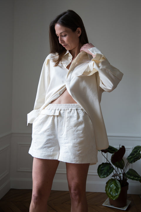 Lena is wearing White Canvas sustainable floral jacquard short shorts, size S. The short shorts have minimal modern aesthetics design allowing comfort and bringing self-confidence. This unique piece is made locally in Paris to reduce environmental impact and guarantee high quality and durability of the products.