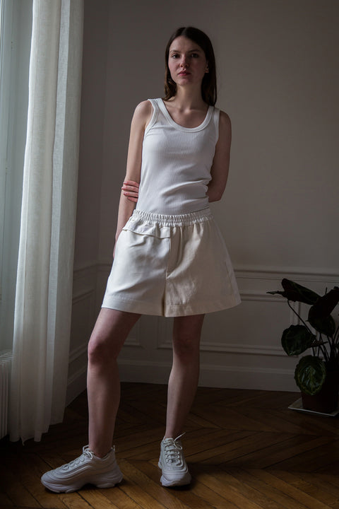 Dalva is wearing White Canvas sustainable mixed fabrics short shorts, size M. The short shorts have minimal modern aesthetics design allowing comfort and bringing self-confidence. This unique piece is made locally in Paris to reduce environmental impact and guarantee high quality and durability of the products.