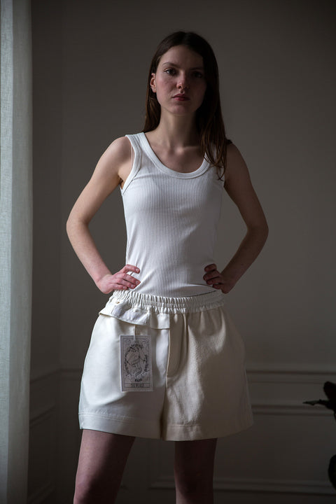 Dalva is wearing White Canvas sustainable mixed fabrics short shorts, size M. The short shorts have minimal modern aesthetics design allowing comfort and bringing self-confidence. This unique piece is made locally in Paris to reduce environmental impact and guarantee high quality and durability of the products.
