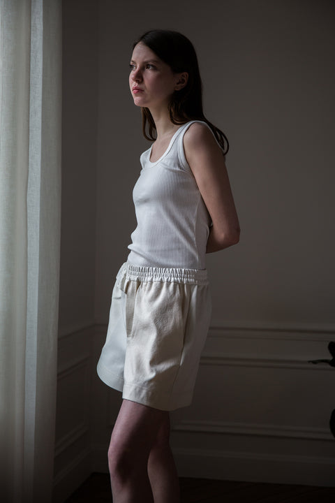 Dalva is wearing White Canvas sustainable mixed fabrics short shorts, size M. The short shorts have minimal modern aesthetics design allowing comfort and bringing self-confidence. This unique piece is made locally in Paris to reduce environmental impact and guarantee high quality and durability of the products.