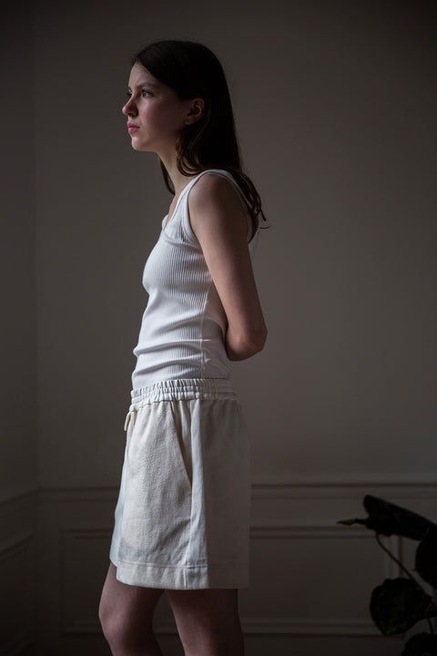 Dalva is wearing White Canvas sustainable mixed fabrics short shorts, size M. The short shorts have minimal modern aesthetics design allowing comfort and bringing self-confidence. This unique piece is made locally in Paris to reduce environmental impact and guarantee high quality and durability of the products.