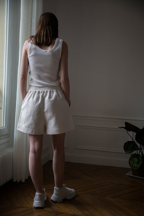 Dalva is wearing White Canvas sustainable mixed fabrics short shorts, size M. The short shorts have minimal modern aesthetics design allowing comfort and bringing self-confidence. This unique piece is made locally in Paris to reduce environmental impact and guarantee high quality and durability of the products.