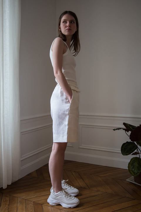 Dalva is wearing White Canvas sustainable textured genderless casual shorts, size S. The textured shorts have minimal modern aesthetics design allowing comfort and bringing self-confidence. This unique piece is made locally in Paris to reduce environmental impact and guarantee high quality and durability of the products.