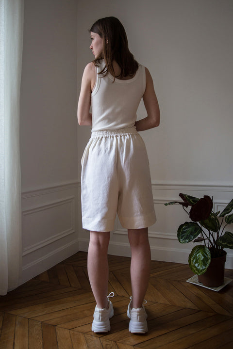 Dalva is wearing White Canvas sustainable textured genderless casual shorts, size S. The textured shorts have minimal modern aesthetics design allowing comfort and bringing self-confidence. This unique piece is made locally in Paris to reduce environmental impact and guarantee high quality and durability of the products.