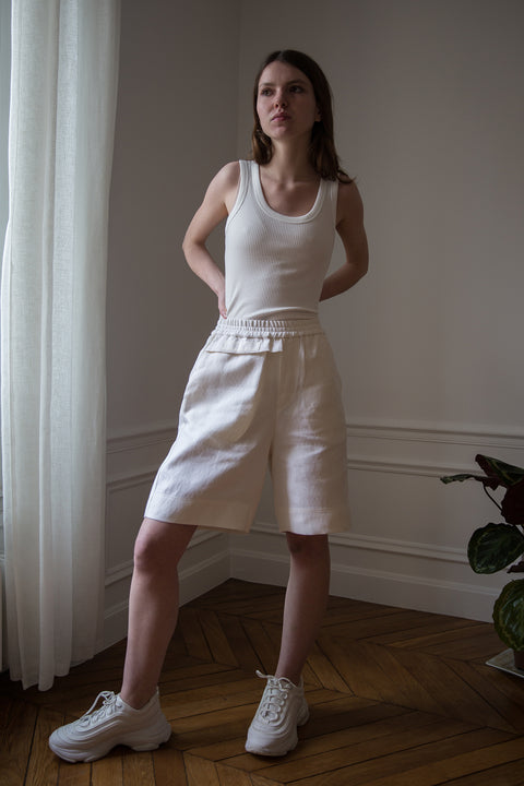 Dalva is wearing White Canvas sustainable textured genderless casual shorts, size S. The textured shorts have minimal modern aesthetics design allowing comfort and bringing self-confidence. This unique piece is made locally in Paris to reduce environmental impact and guarantee high quality and durability of the products.