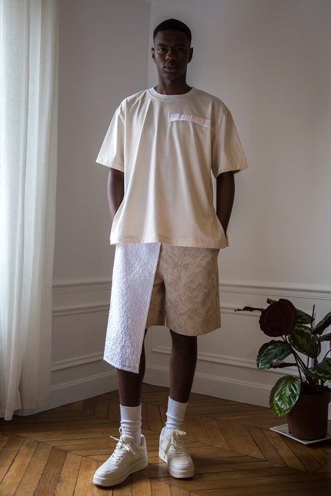 Thierno is wearing White Canvas sustainable cotton jacquard genderless casual shorts, size S. The jacquard shorts have minimal modern aesthetics design allowing comfort and bringing self-confidence. This unique piece is made locally in Paris to reduce environmental impact and guarantee high quality and durability of the products.