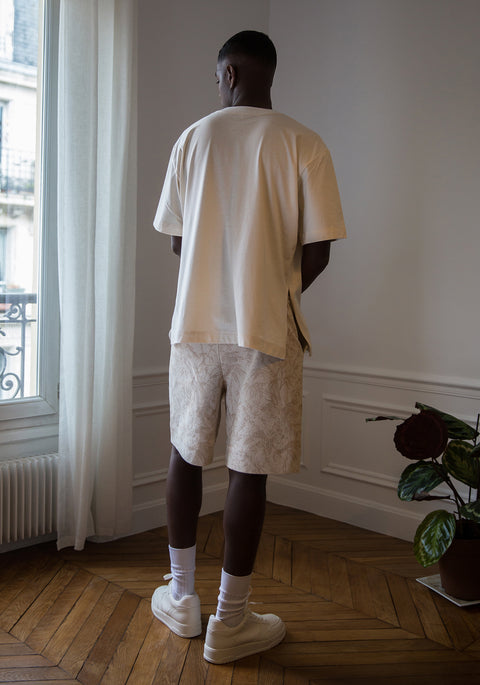 Thierno is wearing White Canvas sustainable cotton jacquard genderless casual shorts, size S. The jacquard shorts have minimal modern aesthetics design allowing comfort and bringing self-confidence. This unique piece is made locally in Paris to reduce environmental impact and guarantee high quality and durability of the products.