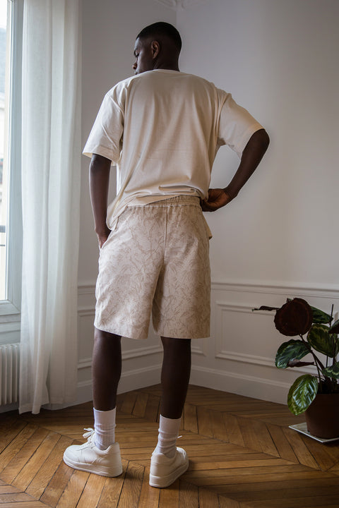 Thierno is wearing White Canvas sustainable cotton jacquard genderless casual shorts, size S. The jacquard shorts have minimal modern aesthetics design allowing comfort and bringing self-confidence. This unique piece is made locally in Paris to reduce environmental impact and guarantee high quality and durability of the products.