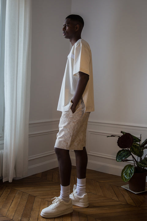 Thierno is wearing White Canvas sustainable cotton jacquard genderless casual shorts, size S. The jacquard shorts have minimal modern aesthetics design allowing comfort and bringing self-confidence. This unique piece is made locally in Paris to reduce environmental impact and guarantee high quality and durability of the products.