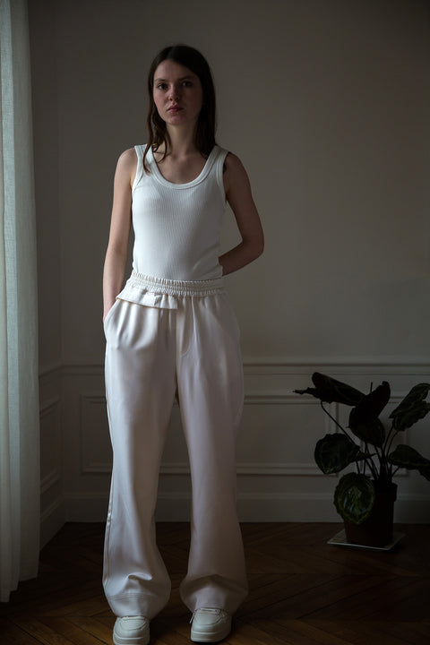 Dalva is wearing White Canvas sustainable light wool genderless, seasonless casual trousers, size S. The light wool trousers have minimal modern aesthetics design allowing comfort and bringing self-confidence. This unique piece is made locally in Paris to reduce environmental impact and guarantee high quality and durability of the products.