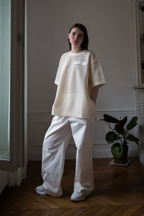 Dalva is wearing White Canvas sustainable cotton stripes genderless, seasonless casual checks trousers, size M. The white cotton stripes trousers have minimal modern aesthetics design allowing comfort and bringing self-confidence. This unique piece is made locally in Paris to reduce environmental impact and guarantee high quality and durability of the products.