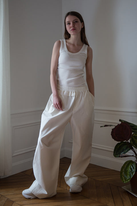 Dalva is wearing White Canvas sustainable cotton stripes genderless, seasonless casual checks trousers, size L. The white cotton stripes trousers have minimal modern aesthetics design allowing comfort and bringing self-confidence. This unique piece is made locally in Paris to reduce environmental impact and guarantee high quality and durability of the products.