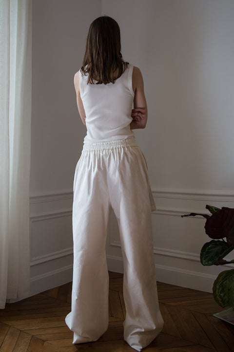 Dalva is wearing White Canvas sustainable cotton stripes genderless, seasonless casual checks trousers, size L. The white cotton stripes trousers have minimal modern aesthetics design allowing comfort and bringing self-confidence. This unique piece is made locally in Paris to reduce environmental impact and guarantee high quality and durability of the products.