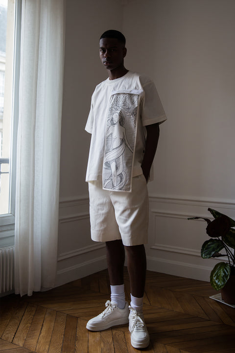 Thierno is wearing White Canvas sustainable white, oversized, genderless, seasonless t-shirt, one size. The cotton stripes t-shirt has minimal modern aesthetics design allowing comfort and bringing self-confidence. This unique piece is made locally in Paris to reduce environmental impact and guarantee high quality and durability of the products. 