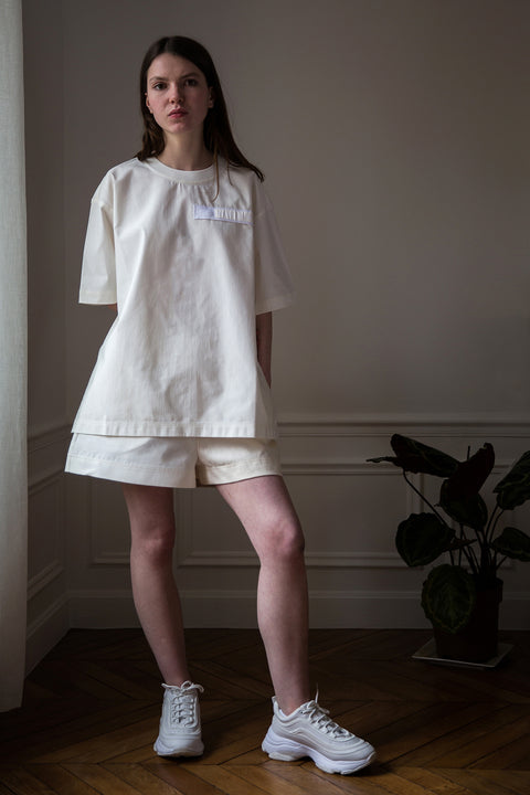 Dalva is wearing White Canvas sustainable white, oversized, genderless, seasonless t-shirt, one size. The cotton textured t-shirt has minimal modern aesthetics design allowing comfort and bringing self-confidence. This unique piece is made locally in Paris to reduce environmental impact and guarantee high quality and durability of the products. 