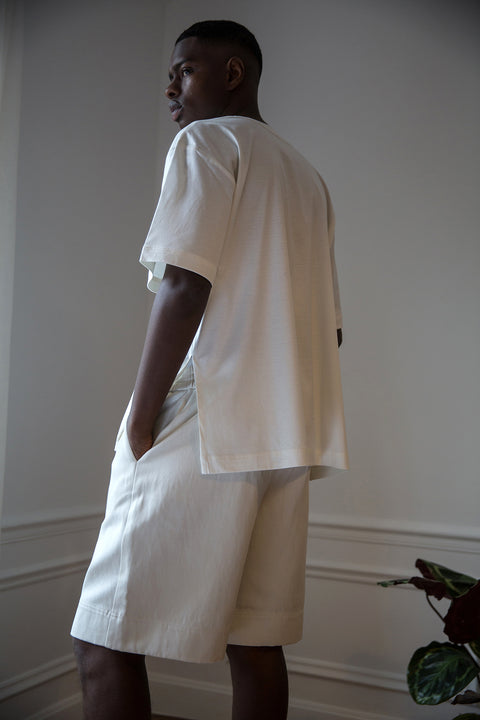 Thierno is wearing White Canvas sustainable off white cotton jersey oversized, genderless, seasonless t-shirt, one size. The off white cotton jersey t-shirt has minimal modern aesthetics design allowing comfort and bringing self-confidence. This unique piece is made locally in Paris to reduce environmental impact and guarantee high quality and durability of the products. 