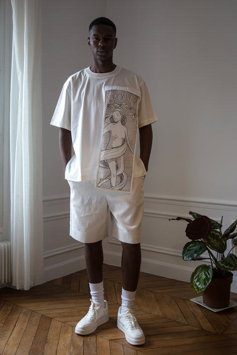 Thierno is wearing White Canvas sustainable off white cotton jersey oversized, genderless, seasonless t-shirt, one size. The off white cotton jersey t-shirt has minimal modern aesthetics design allowing comfort and bringing self-confidence. This unique piece is made locally in Paris to reduce environmental impact and guarantee high quality and durability of the products. 