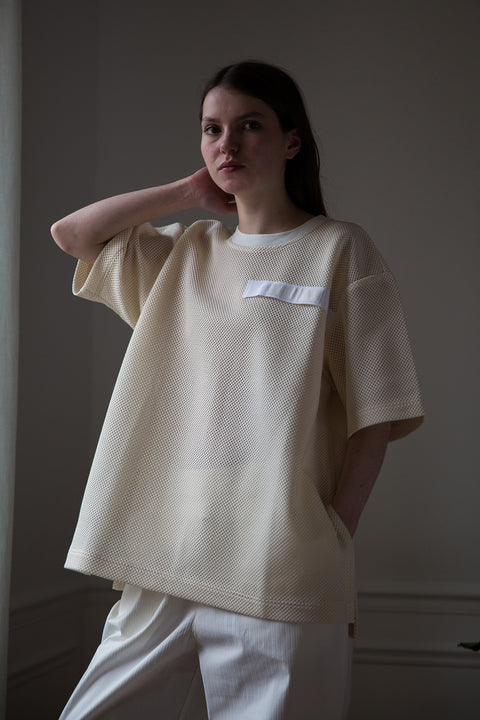 Dalva is wearing White Canvas sustainable mesh oversized, genderless, seasonless t-shirt, one size. The mesh t-shirt has minimal modern aesthetics design allowing comfort and bringing self-confidence. This unique piece is made locally in Paris to reduce environmental impact and guarantee high quality and durability of the products.  
