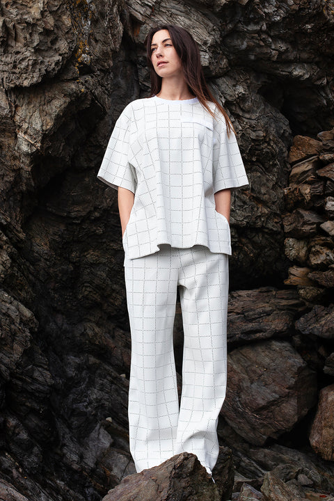 Romane is wearing White Canvas sustainable light grey color, genderless, seasonless casual checks trousers, size S. The Essential checks trousers have minimal modern aesthetics design allowing comfort and bringing self-confidence. This unique piece is made locally in Paris to reduce environmental impact and guarantee high quality and durability of the products. 