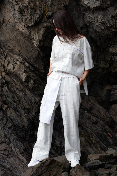 Romane is wearing the White Canvas ESSENTIAL T-SHIRT AND TROUSERS styled with the silver checks and tweed vertical fabric panel made from leftover deadstock fabrics. The silver checks and tweed panel is an exclusive unique sustainable piece made in France. It is made to be attached to the essential pieces to personalize them and wear them your unique way.