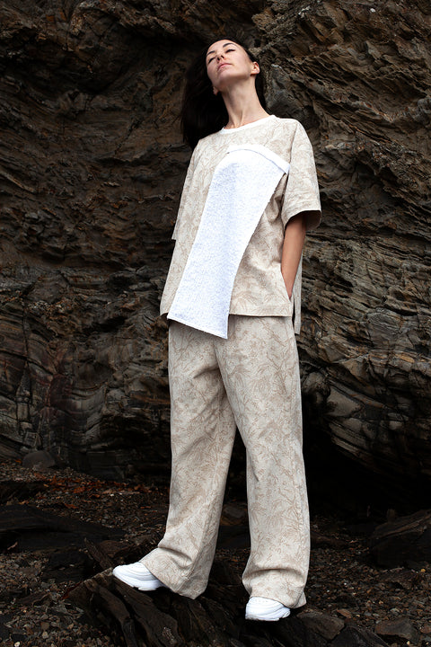 Romane is wearing the White Canvas ESSENTIAL T-SHIRT AND TROUSERS styled with the white tweed vertical fabric panel made from leftover deadstock fabrics. The white tweed panel is an exclusive unique sustainable piece made in France. It is made to be attached to the essential pieces to personalize them and wear them your unique way.