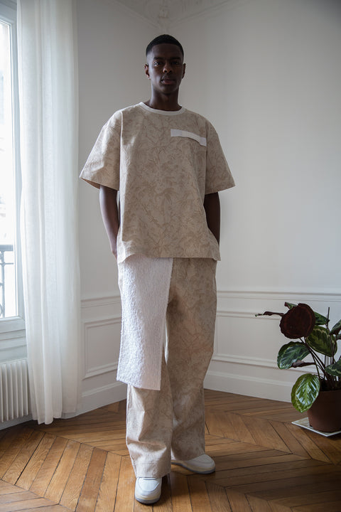 Thierno is wearing White Canvas jacquard natural color, oversized, genderless, seasonless casual t-shirt, one size. The Essential jacquard t-shirt has minimal modern aesthetics design allowing comfort and bringing self-confidence. This unique piece is made locally in Paris to reduce environmental impact and guarantee high quality and durability of the products. 