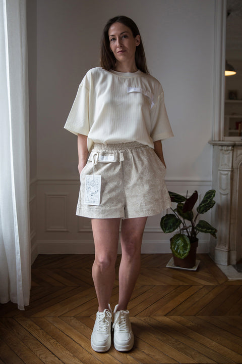 Lena is wearing White Canvas sustainable light weight oversized, genderless, seasonless t-shirt, one size. The light weight t-shirt has minimal modern aesthetics design allowing comfort and bringing self-confidence. This unique piece is made locally in Paris to reduce environmental impact and guarantee high quality and durability of the products. 