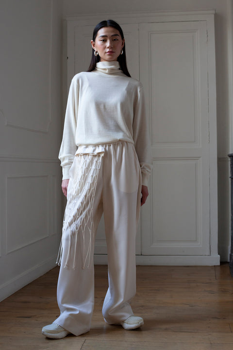 SiJia is wearing the White Canvas wool trousers styled with the net vertical panel with recycled beads made from leftover deadstock fabrics. The net vertical panel with recycled beads is an exclusive unique sustainable piece made in France. It is made to be attached to the essential pieces to personalize them and wear them your unique way.
