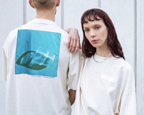 Two models are wearing the White Canvas Originals sustainable, oversized, genderless t-shirt, one size. The organic cotton natural color t-shirt has minimal modern aesthetics design allowing comfort and bringing self-confidence. This limited edition collection is made in Portugal to reduce environmental impact and guarantee high quality and durability of the products. There is a photo by the photographer Henrique Soares at the back of the t-shirt.