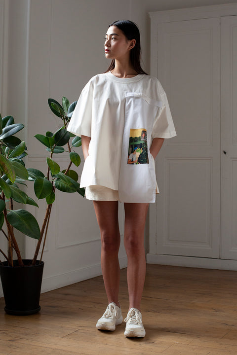 SiJia is wearing the White Canvas cotton t-shirt styled with the Flower guy vertical panel made from deadstock cotton poplin. The panel has an exclusive print of a photo by the photographer Henrique Soares. Attach the panel to the essential pieces to personalize them and wear them your unique way. It is the perfect creative summer accessory.