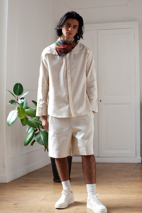 Medhi is wearing the White Canvas essential shirt styled with the Hand triangular panel and bandana made from deadstock cotton poplin. The bandana has an exclusive print of a photo by the photographer Henrique Soares. Attach the panel to the essential pieces to personalize them and wear them your unique way. It is the perfect creative summer accessory.