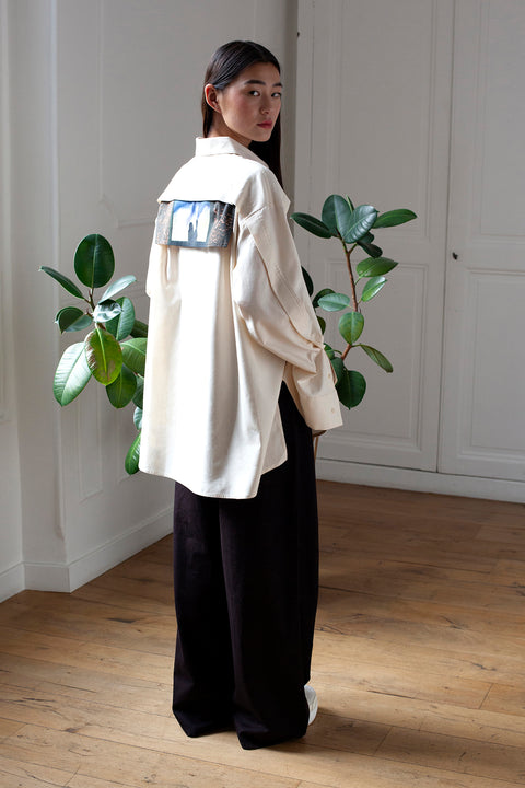 SiJia is wearing the White Canvas ESSENTIAL SHIRT styled with the Shadows horizontal panel made from deadstock white cotton poplin. The panel has an exclusive print of a photo by the photographer Henrique Soares. Attach the panel to the essential pieces to personalize them and wear them your unique way. It is the perfect creative autumn accessory.