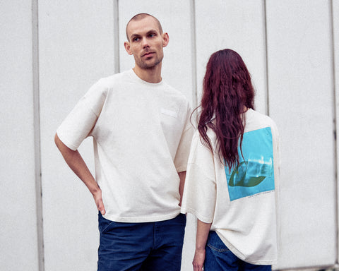 Two models are wearing the White Canvas Originals sustainable, oversized, genderless t-shirt, one size. The organic cotton natural color t-shirt has minimal modern aesthetics design allowing comfort and bringing self-confidence. This limited edition collection is made in Portugal to reduce environmental impact and guarantee high quality and durability of the products. There is a photo by the photographer Henrique Soares at the back of the t-shirt.