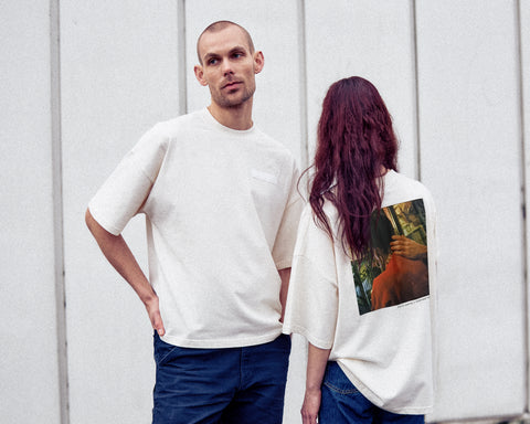 Two models are wearing the White Canvas Originals sustainable, oversized, genderless t-shirt, one size. The organic cotton natural color t-shirt has minimal modern aesthetics design allowing comfort and bringing self-confidence. This limited edition collection is made in Portugal to reduce environmental impact and guarantee high quality and durability of the products. There is a photo by the photographer Henrique Soares at the back of the t-shirt.