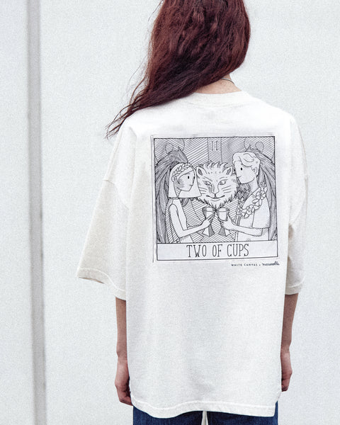 A female model is wearing the White Canvas Originals sustainable, oversized, genderless t-shirt, one size. The organic cotton, natural color t-shirt has minimal modern aesthetics design allowing comfort and bringing self-confidence. This limited edition collection is made in Portugal to reduce environmental impact and guarantee high quality and durability of the products. There is an illustration by the artist Maria Robla at the back.